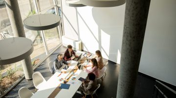 Grupo de personas sentadas en un escritorio compartido usando sus dispositivos