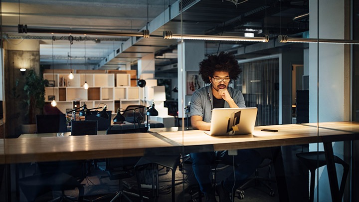 Zakenman die op laptop werkt terwijl hij aan een bureau in een kantoor zit