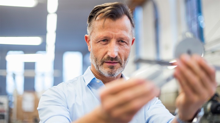 Mature businessman examining quality of component