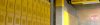 A school hallway lined with bright yellow metal lockers and an illuminated EXIT sign in the background