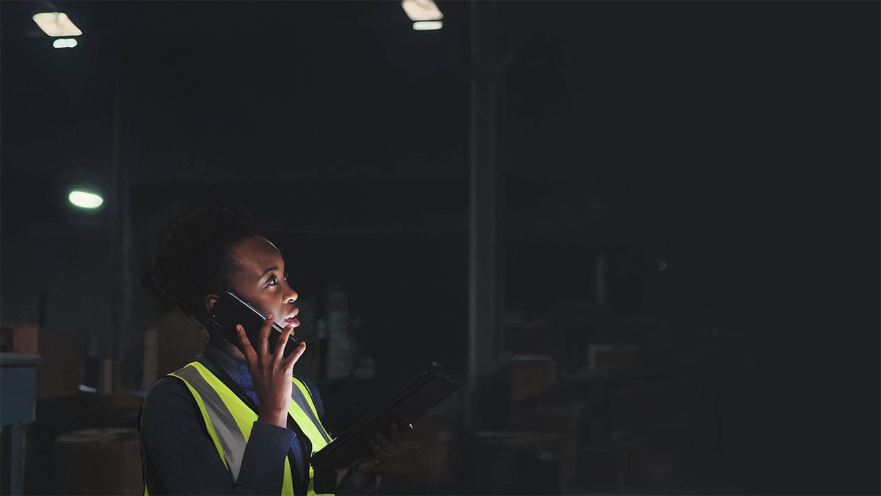 Warehouse worker on a phone in a dimly lit industrial space