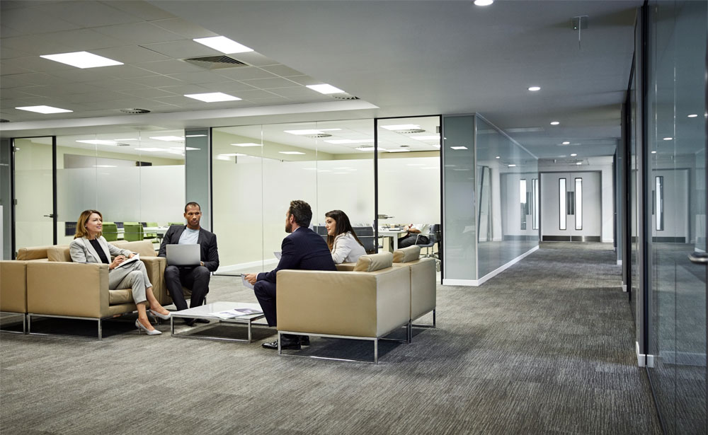 Four colleagues in discussion in a well-lit office lounge area