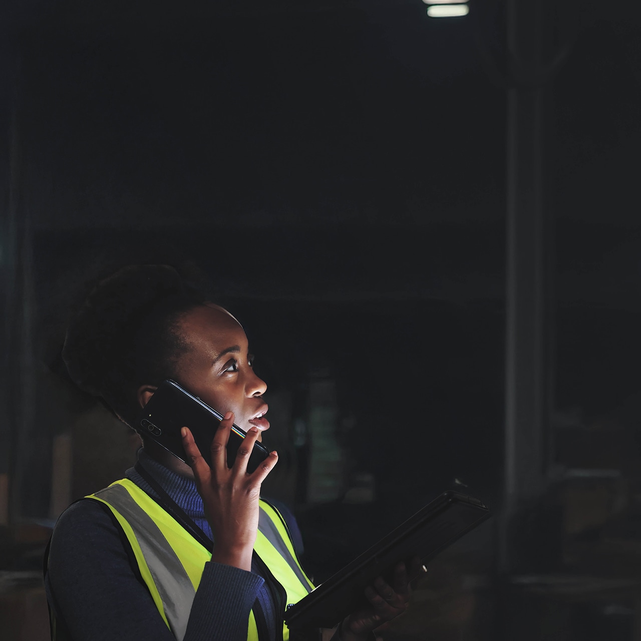 Warehouse worker on a phone in a dimly lit industrial space