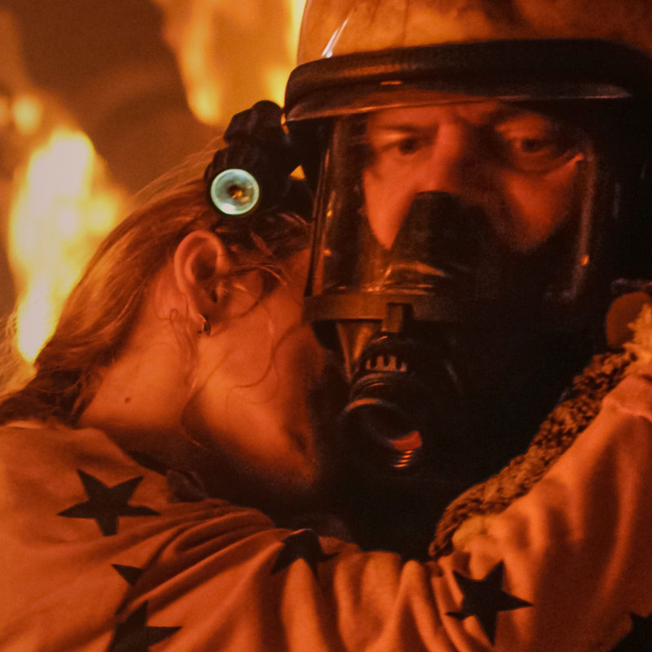 A firefighter carrying a person to safety amid flames and smoke