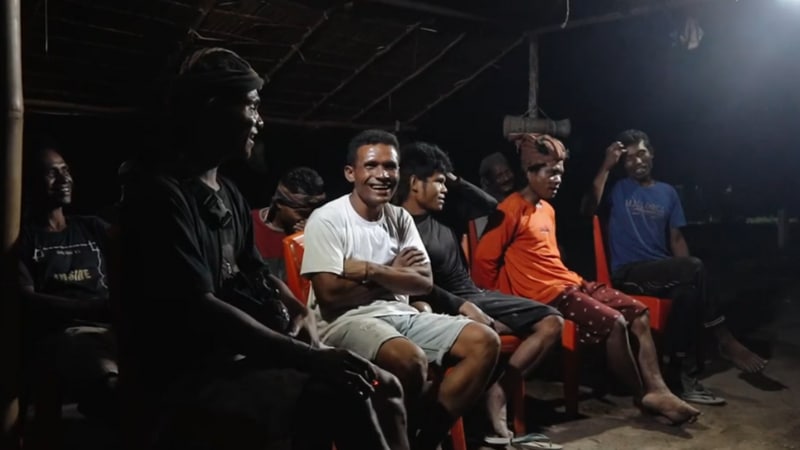 villagers gather for a meeting at night under a solar floodlight
