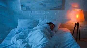 Woman sleeping in bed with regulating light on