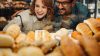 Person smiling behind a bakery counter with bread