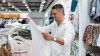 Man holding white garment in retail store
