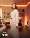 Pessoa numa sala de estar com iluminação ambiente Philips Hue.
